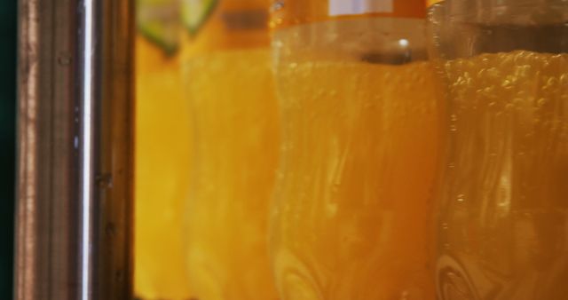 Bright and vibrant image showcasing close-up of several bottles filled with fresh orange juice, likely freshly packed or arranged. This can be used in advertising and marketing for beverage companies, health food magazines, or any promotional material emphasizing healthy refreshment.