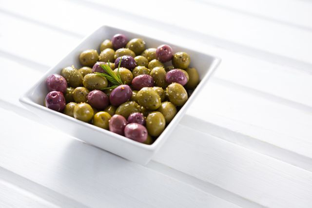 Marinated olives in white bowl on wooden table