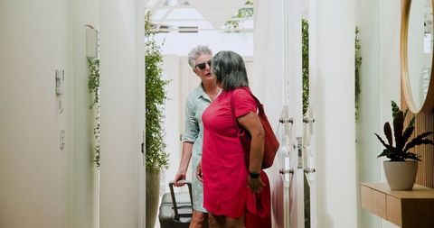 Senior Lesbian Couple Arriving at Hotel with Luggage