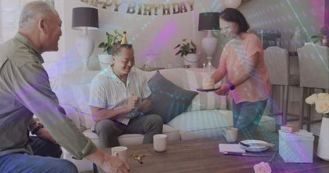 Group celebrating birthday at home with cake and candles in cozy living room with banner