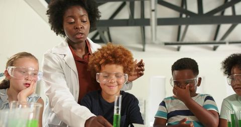Black teacher guiding diverse students through colorful chemistry experiment in school lab