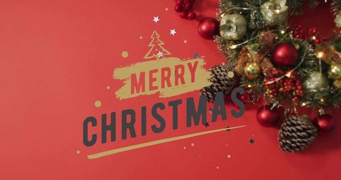 Merry christmas typography with gold baubles, pine cones and festive wreath on red background