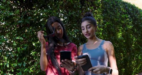 Diverse Female Friends Bonding with Smartphones in Sunlit Garden