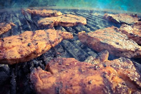 Smoky grilled pork chops sizzling over charcoal grill with golden sear and marinade