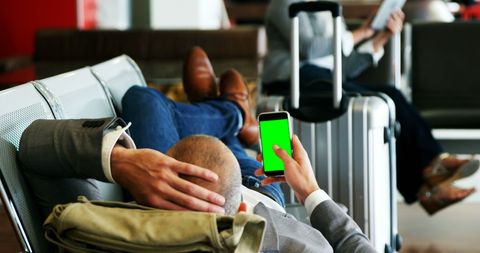 Businessman relaxing at airport lounge using smartphone