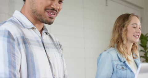 Young diverse coworkers smiling and collaborating around laptop in bright modern workspace