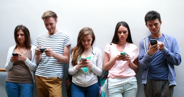 A group of young adults engaging with their smartphones, highlighting the modern-day reliance on technology for communication. Suitable for articles related to social media usage, technology dependence, digital communication, and modern lifestyle trends.