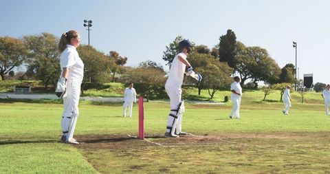 Female Cricket Teammates in Intense Outdoor Match with Pink Stumps