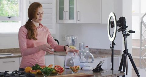 Woman filming culinary tutorial in modern kitchen