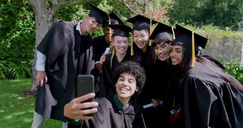 Multiracial Graduates Taking Selfie While Celebrating Commencement on Campus Lawn