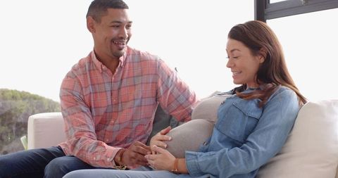 Expectant couple embracing parenthood sitting on cozy sofa