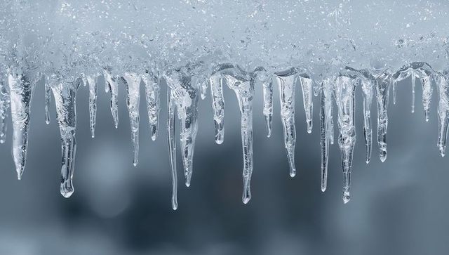Glinting Icicles Hanging from Snow-Covered Eave with Dripping Frost and Crystal Clarity
