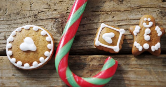 A festive arrangement showcases gingerbread cookies and a candy cane on a wooden surface, with copy space. These treats are often associated with holiday celebrations and the joy of seasonal baking.