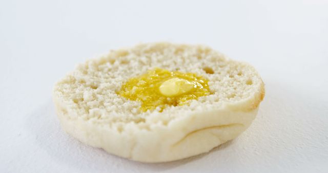 A close-up view of an English muffin with butter and honey, with copy space. Its crumbly texture and the melting pat of butter atop make it an appetizing breakfast choice.
