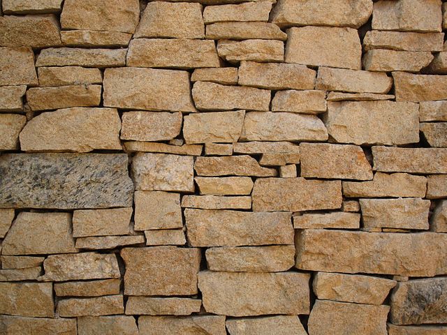 Stone wall with irregular brick pattern showcasing natural texture and rugged appeal. Ideal for use in backgrounds, design projects, advertisements, and websites focused on construction, architecture, or rustic themes.