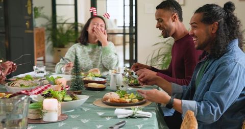 Diverse Friends Laughing at Holiday Dinner Table Celebrating