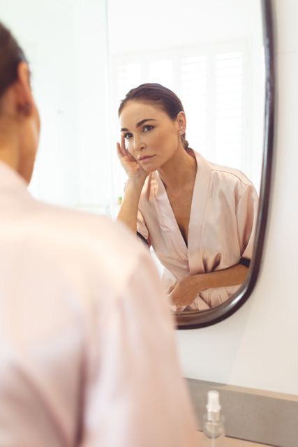 Beautiful woman looking at her face in the mirror at bathroom