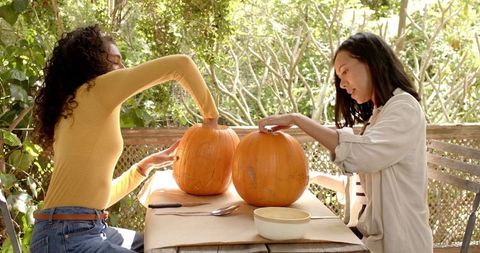 Multiracial Friends Carving Pumpkins in Autumn Atmosphere
