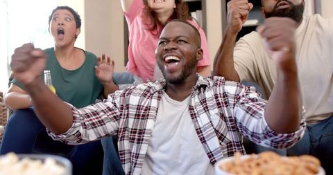 Group of Friends Celebrating Victory with Snacks in Living Room
