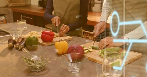 Women collaborating in kitchen chopping fresh vegetables on counter with digital overlay