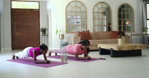 African american mother daughter holding forearm planks during at-home fitness session