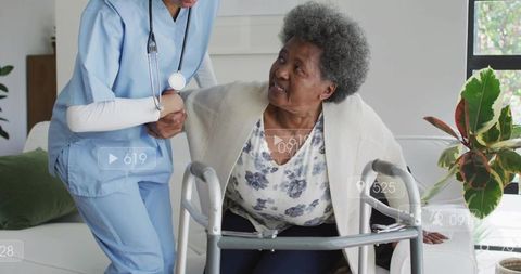 Nurse assisting senior using walker during home care visit in comfortable living room