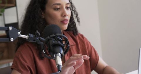 African american woman recording podcast in minimal home studio with laptop and mic