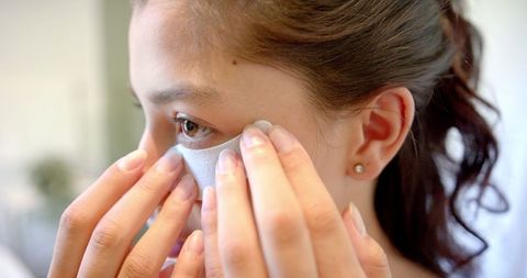 Teenage girl applying under-eye mask at home