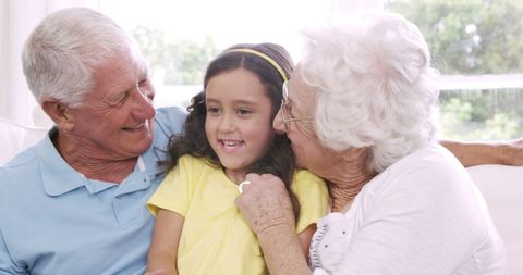 Joyful Grandparents Enjoying Time with Granddaughter on Sofa