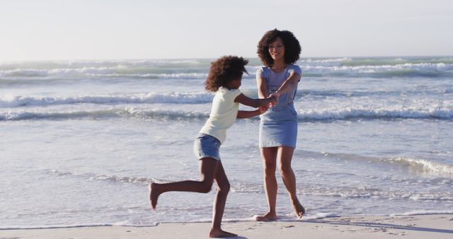 African american mother and her daughter playing on the beach. healthy outdoor leisure time by the sea.
