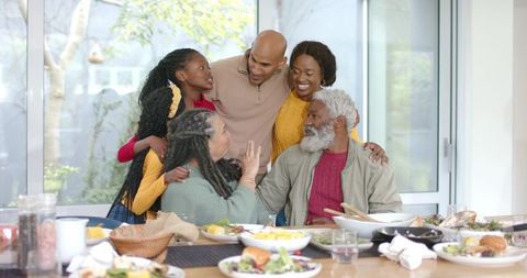 Multigenerational family gathering and sharing joyful meal at sunlit dining table