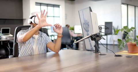 Man Using VR Headset for Virtual Interface Interaction in Modern Office