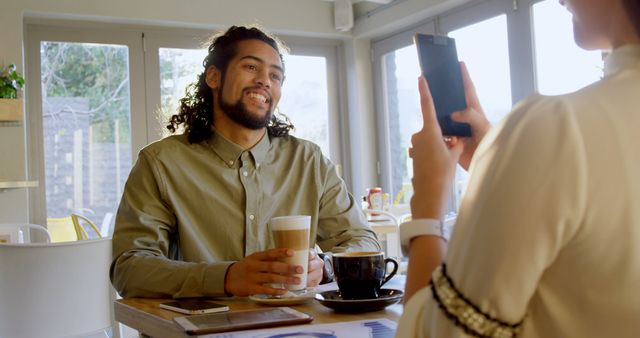 Smiling Man Enjoying Coffee Captured by Woman at Café - Download Free Stock Images Pikwizard.com