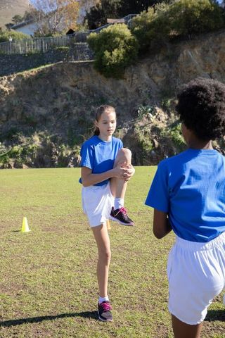 Teenage Teammates Stretching on Sports Field in Blue Uniforms
