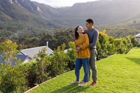 Couple embracing on lawn overlooking mountain valley, cozy fall sweaters, outdoor portrait