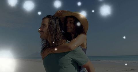 Joyful couple embracing on beach with floating orbs