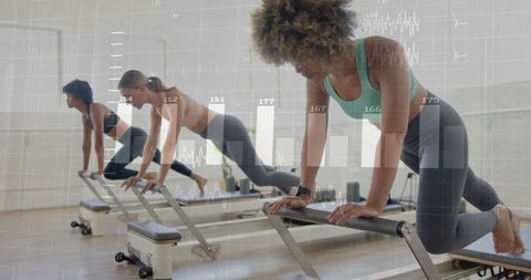 Women Practicing Pilates with Wearable Tech in Modern Studio