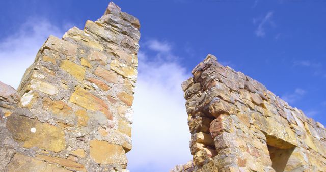 Ancient stone ruins stand against a blue sky, with copy space. Weathered stones tell a story of historical significance and past civilizations.