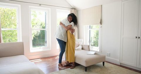 Couple embracing in bright living room with open windows