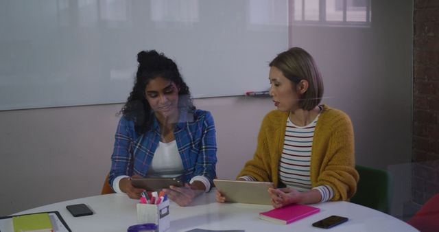 Diverse female business colleagues in discussion at work using digital tablets. independent creative design business.