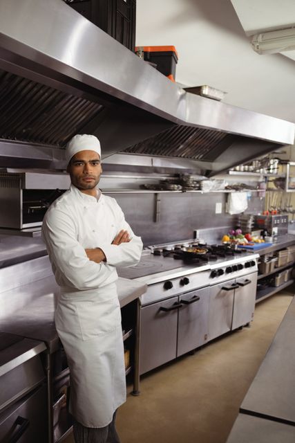 Portrait of confident chef standing with arms crossed in commercial kitchen at restaurant