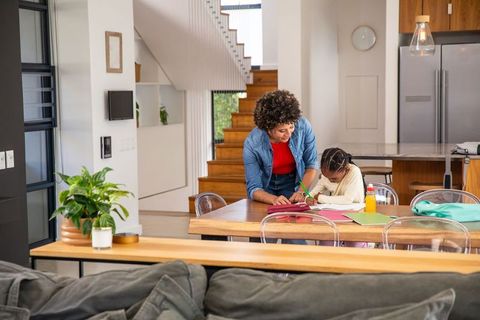 Mother Assisting Child with Homework at Modern Kitchen Table