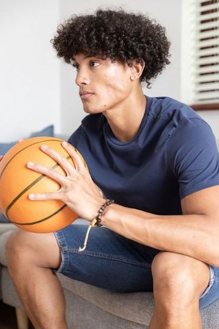 Young African American Man Relaxing at Home with Basketball