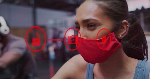 Woman wearing red mask pedaling stationary bike in gym with safety icons overlay