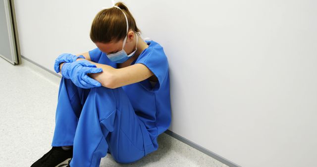 Exhausted Healthcare Worker in PPE Sitting Against Wall - Download Free Stock Images Pikwizard.com