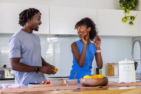 African american couple preparing healthy fruit in modern kitchen enjoying active lifestyle