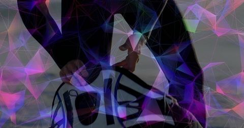 Crouching snowboarder adjusting bindings with vibrant polygon network overlay, outdoor