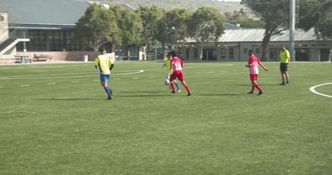 Youth players in soccer game on school field ensuring teamwork