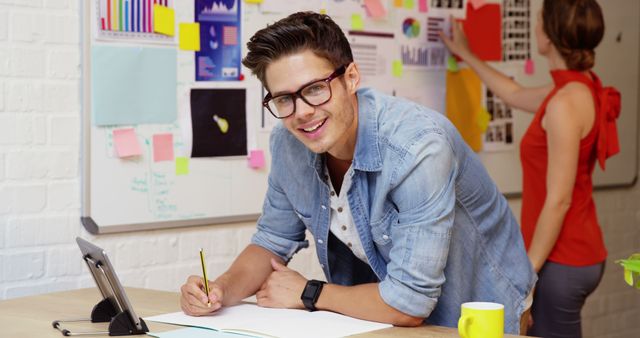 Young Office Worker Writing at Desk Smiling - Download Free Stock Images Pikwizard.com