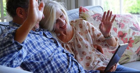 Happy Senior Couple Video Calling Family on Tablet at Home